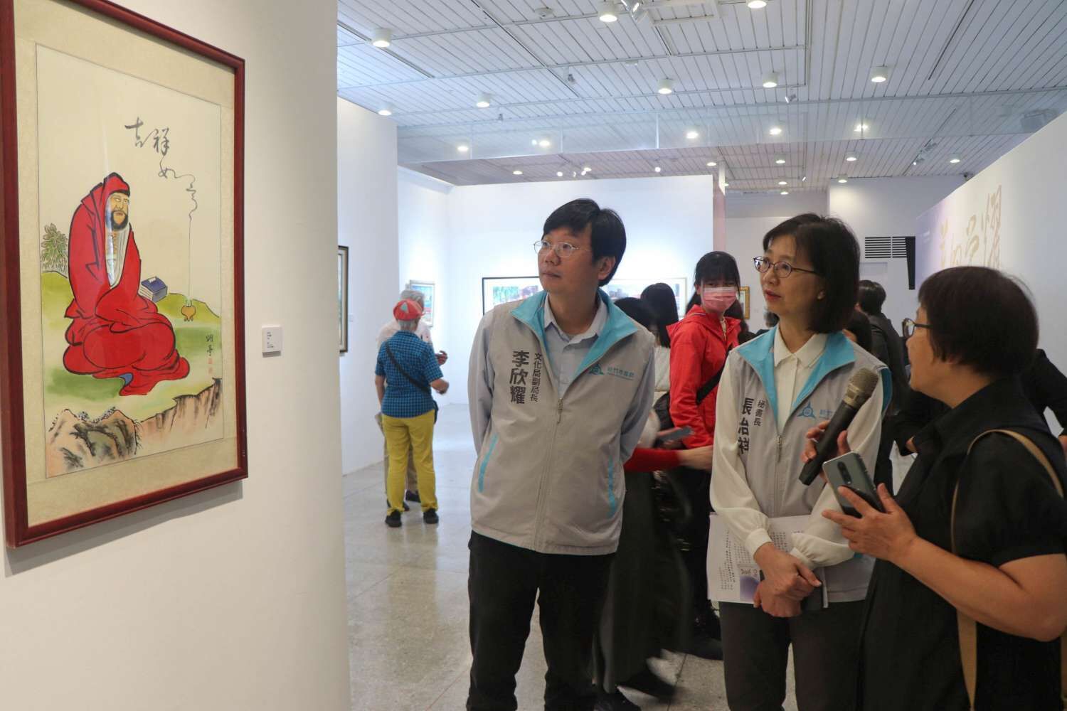 參展藝術家范天送家屬范素鑾，向張秘書長介紹作品。